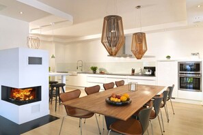 Eine moderne Küche mit einer zentralen Kochinsel, einem eingebauten Kamin und Pendelleuchten.