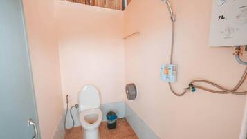 A small bathroom with a toilet, shower, and a wall-mounted control panel.