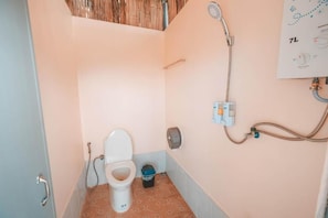 Une petite salle de bain comprenant des toilettes, une douche et un panneau de commande fixé au mur.