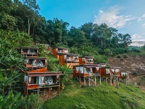 Une série de chalets en bois à plusieurs niveaux, entourés d’une végétation luxuriante et d’arbres.