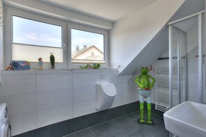 Une salle de bain avec des toilettes, une douche et une fenêtre.