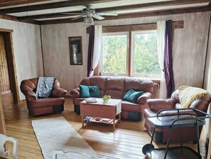 A cozy living room with a brown leather sofa, a coffee table, and a glass table with chairs. - 4 Star Holiday Home in Farosund (Fårösund)