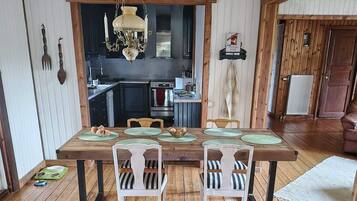 A dining area with a wooden table, white chairs, and a chandelier.