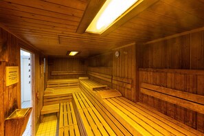 A sauna with wooden benches and a sloped floor. - 2 Raum Appartement im IFA Fehmarn mit Balkon (Fehmarn)