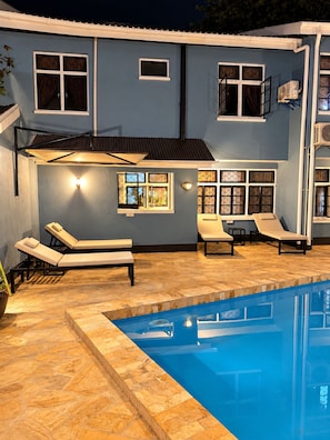 A swimming pool area with lounge chairs and a tiled deck. - B&B HOTEL USHIRIKA (Moshi)