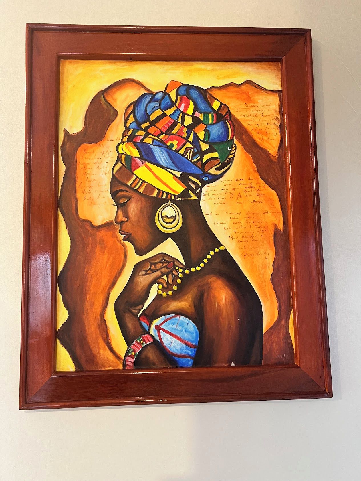 A framed painting of a person with a colorful headpiece and jewelry.