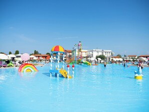 Ein Wasserpark mit Rutschen, einem Pool und Strandsonnenschirmen.