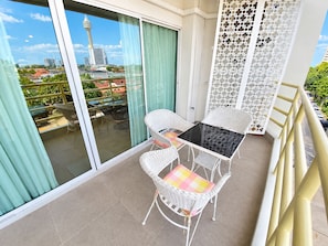 A balcony with a glass door, a table with chairs, and a decorative white partition. - Minutes From the Beach Apartment in Pattaya (Pattaya)