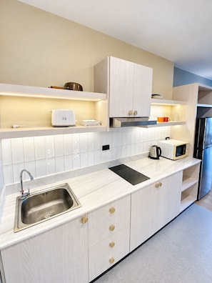 A modern kitchen with a stainless steel sink, a built-in microwave, and a black induction cooktop. - Minutes From the Beach Apartment in Pattaya (Pattaya)