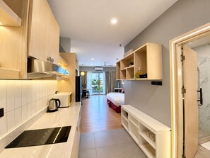 Une chambre d’hôtel moderne équipée d’une kitchenette, d’un lit, d’une salle de bain et offrant une vue sur l’extérieur.