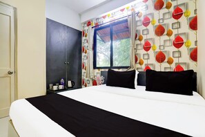 Un dormitorio con cama, armario, ventana y pared con motivos de hojas.