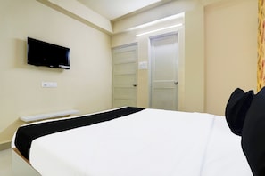 Habitación de hotel con una cama, un televisor de pantalla plana montado en la pared, una puerta y un interruptor de luz.