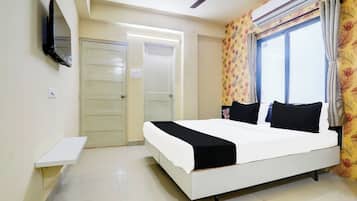 Habitación de hotel con cama, televisor montado en la pared, ventilador de techo y aire acondicionado.