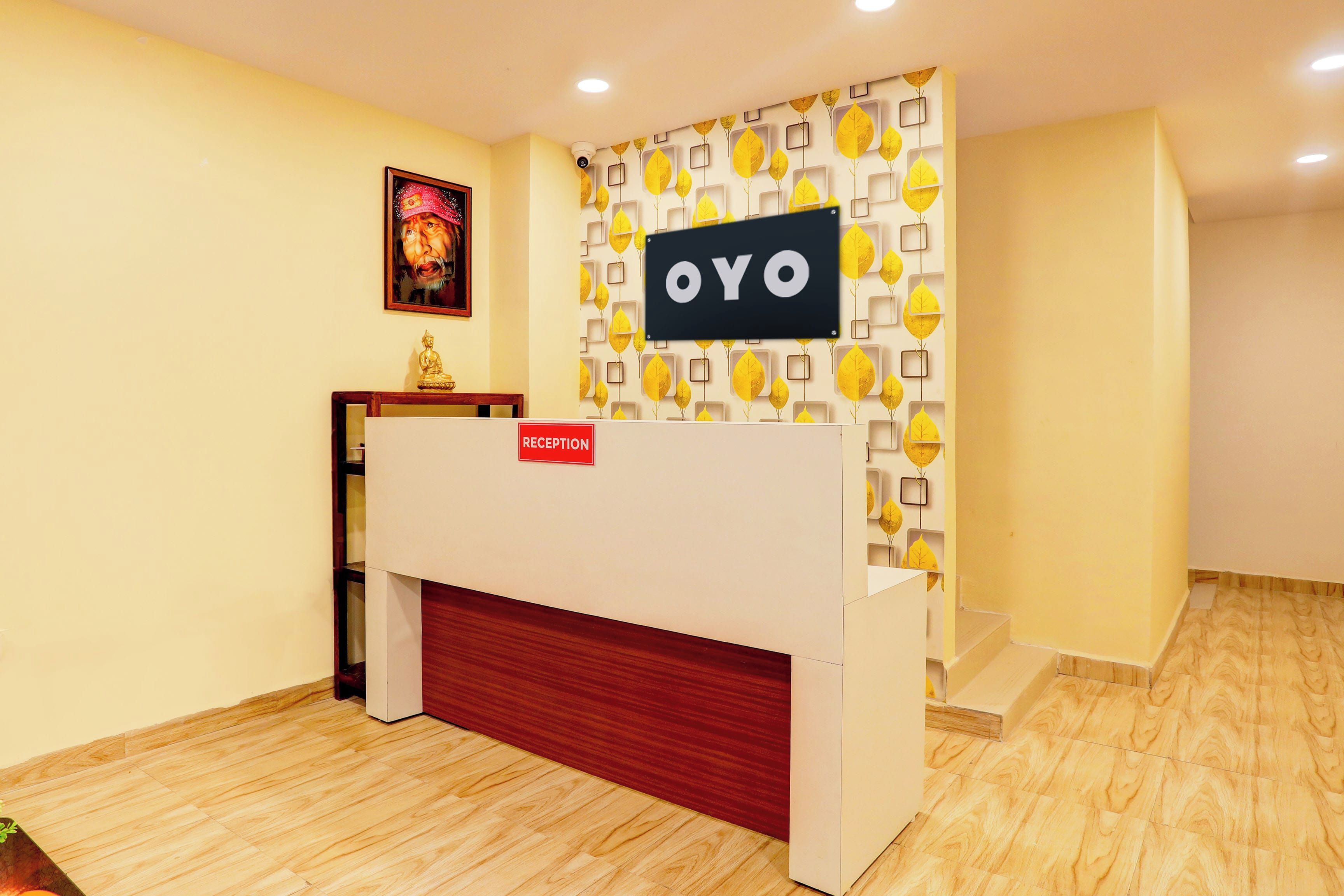 Un mostrador de recepción con un cartel que dice 'RECEPTION', una foto enmarcada arriba y una pared con un diseño de hojas.