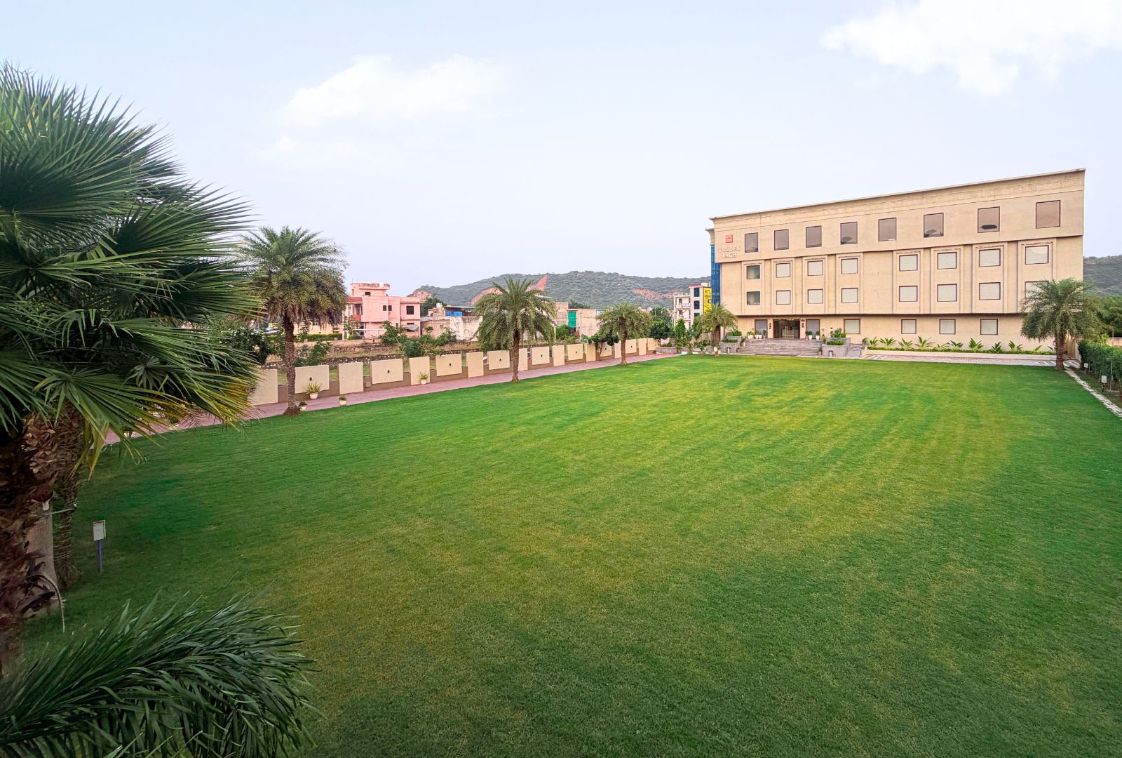 A large, well-maintained grassy area with a building in the background.