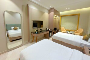 A hotel room with two beds, a desk with a flat-screen TV, a coffee maker, and a chair. - Golden Bagh (Bhakhera)