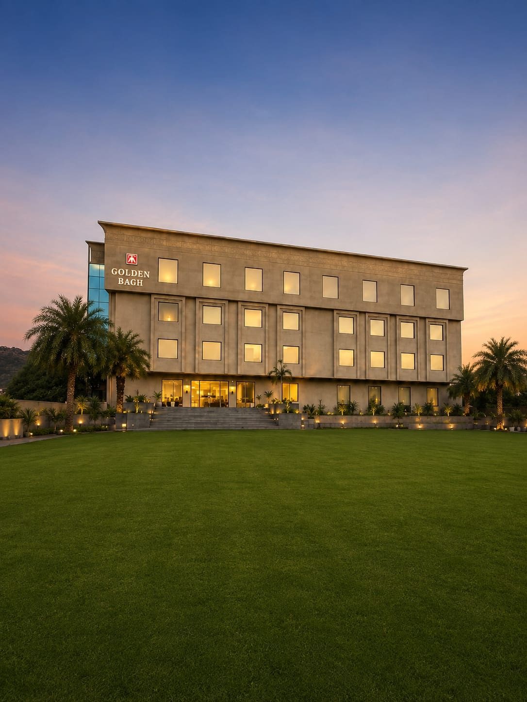 A modern hotel building with a flat facade, large windows, and a well-maintained lawn in front.
