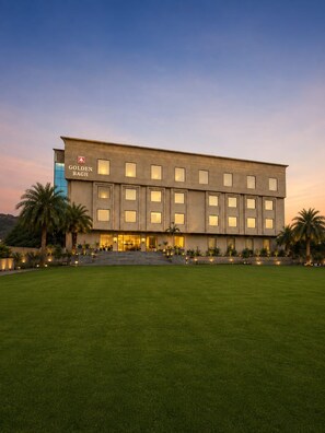 A modern hotel building with a flat facade, large windows, and a well-maintained lawn in front. - Golden Bagh (Bhakhera)