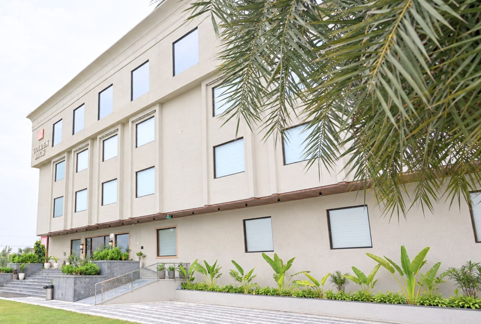A multi-story building with a flat facade, rectangular windows, and a sign that reads 'GOLDEN BAGH.'