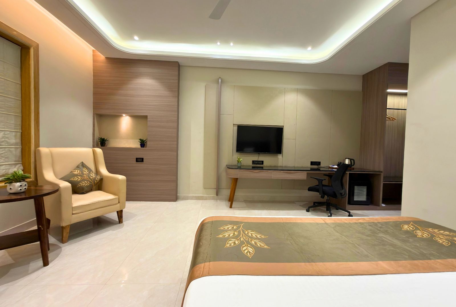 A modern bedroom with a bed, a desk, a chair, and a television.
