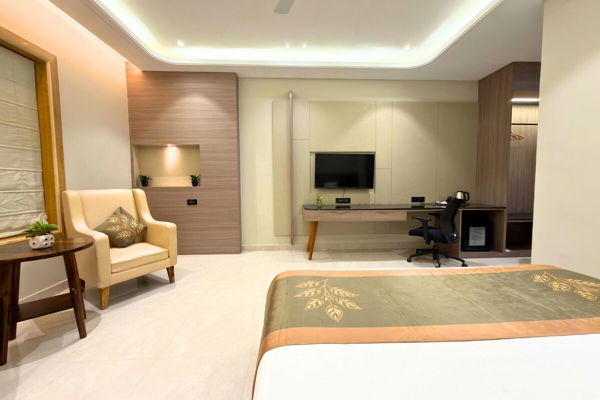 A modern bedroom with a bed, a desk, a chair, and a television.