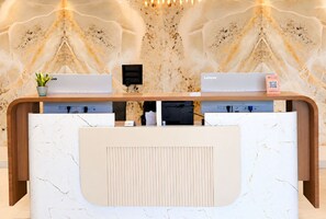 A reception desk with a marble-like pattern, a small plant, a QR code for information, and a 'Welcome' sign. - Golden Bagh (Bhakhera)