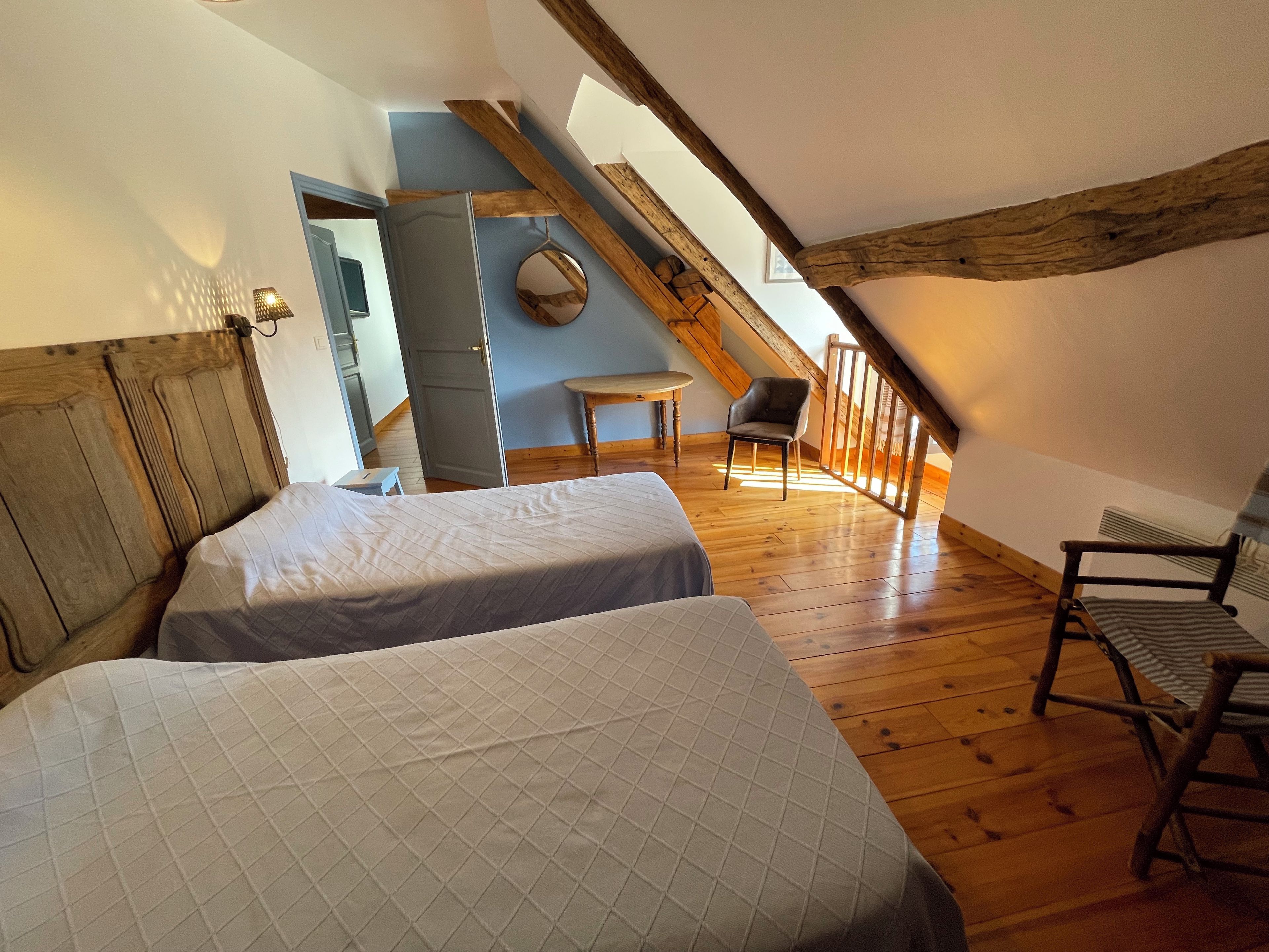 Une chambre avec deux lits, un plafond en bois, une petite table et une chaise.