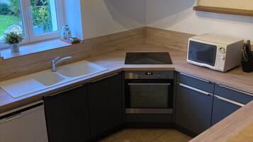 Une cuisine moderne équipée d’un lave-vaisselle, d’un four, d’un four à micro-ondes et d’une fenêtre donnant sur un espace verdoyant.