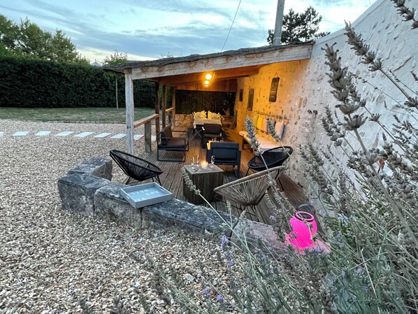 Une terrasse extérieure avec des sièges et une table, entourée d’une zone recouverte de gravier et d’une plateforme en bois.