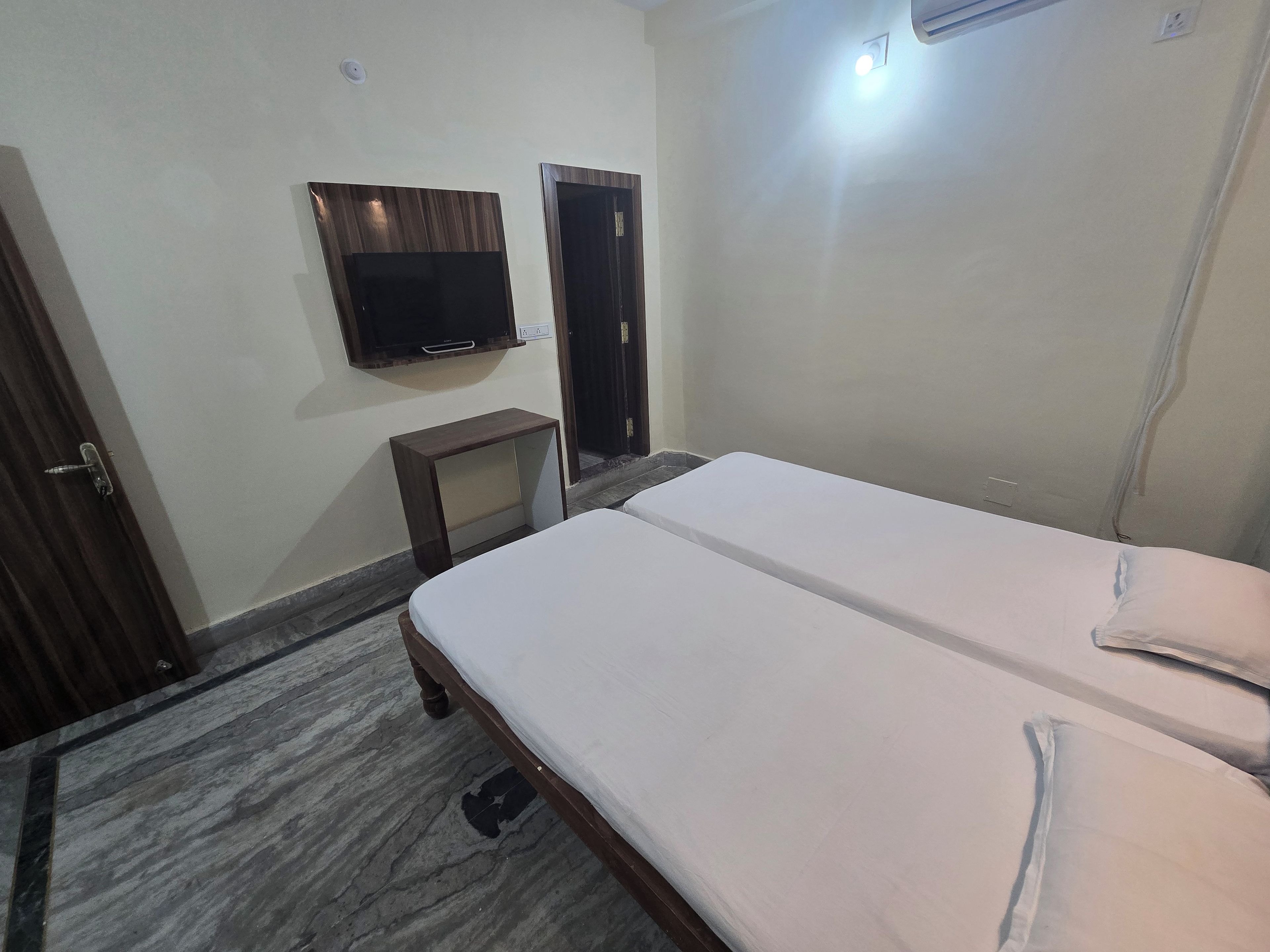 A bedroom with a bed, a TV mounted on the wall, and a door.