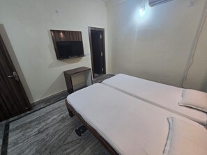 Un dormitorio con una cama, un televisor montado en la pared y una puerta.
