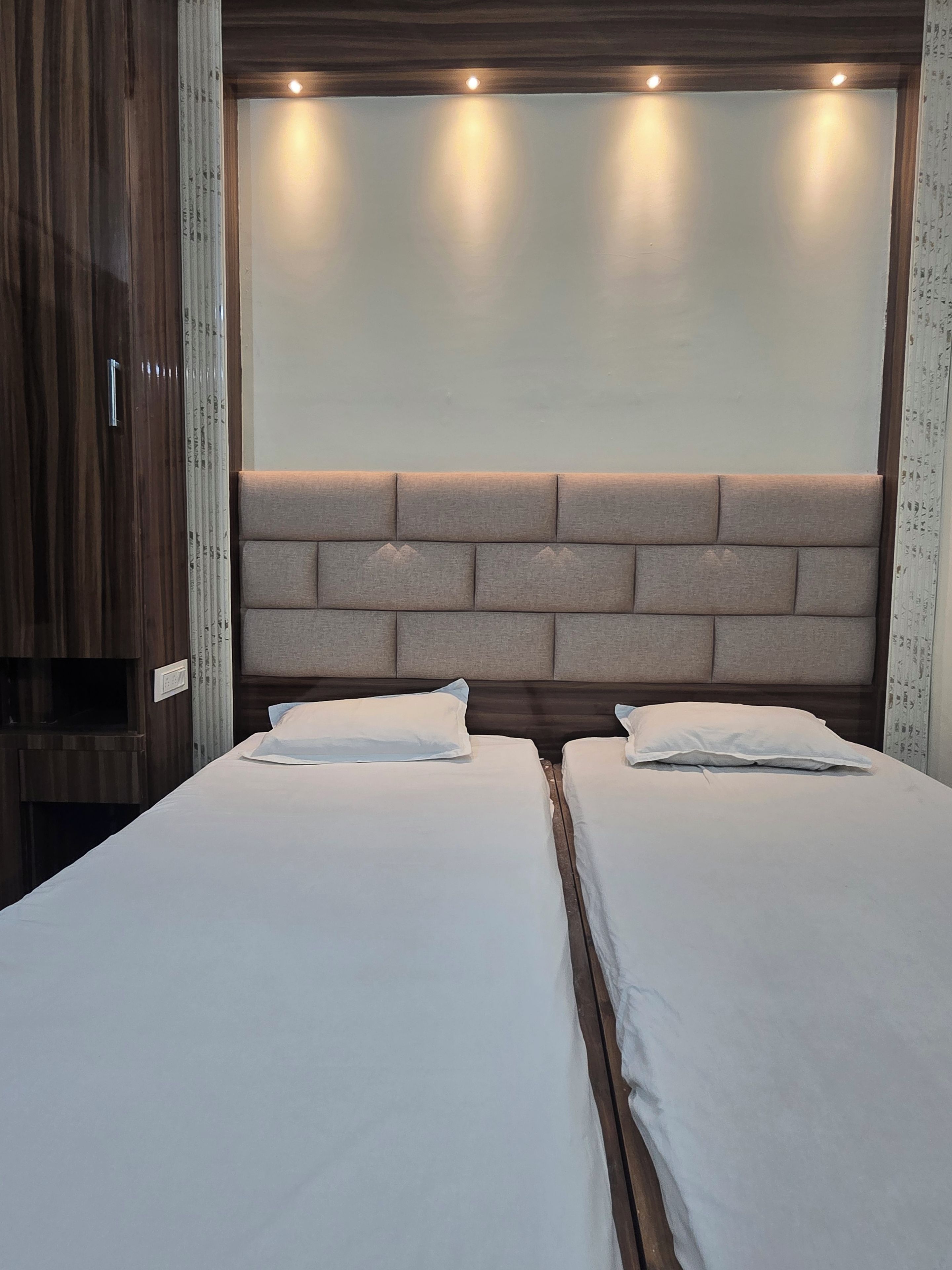 Uma cama de casal com cabeceira com padrão de tijolos e iluminação embutida.