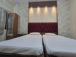 A hotel room with two single beds, a wooden wardrobe, and a decorative headboard. - Sri Sai Guest House (Ranchi)