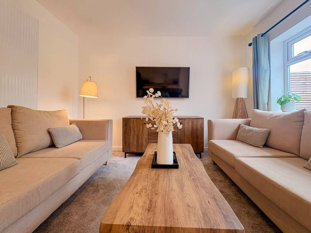 A modern living room with two sofas, a coffee table, a TV, and a lamp.