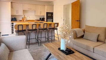 A modern kitchen with white cabinets, a wooden island, and bar stools.