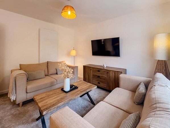 A modern living room with a sofa, a coffee table, and a television.