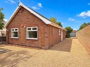 A single-story brick house with a gabled roof, a small front porch, and a gravel driveway. - Bungay Bungalow (Ditchingham)