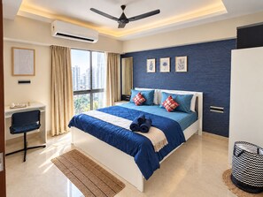 A modern bedroom with a large bed, a desk, and a chair. - The Cozy House 1BHK Near BKC (Mumbai)