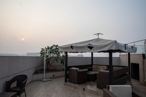 A rooftop terrace with a covered seating area, a small table, and a potted plant. - The Cozy House 1BHK Near BKC (Mumbai)
