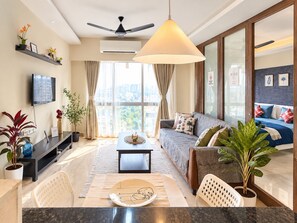 A modern living room with a sofa, coffee table, and a dining area with chairs and a table. - The Cozy House 1BHK Near BKC (Mumbai)