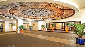 En rummelig lobby med et stort, detaljeret loft og plantepotteskjulere.