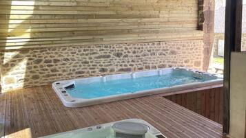 A spa area with two hot tubs and a stone wall.