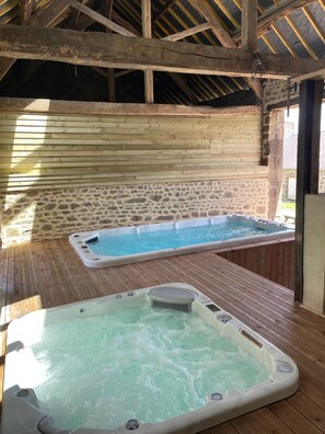 Un espace spa comprenant deux bains à remous et un mur en pierre.