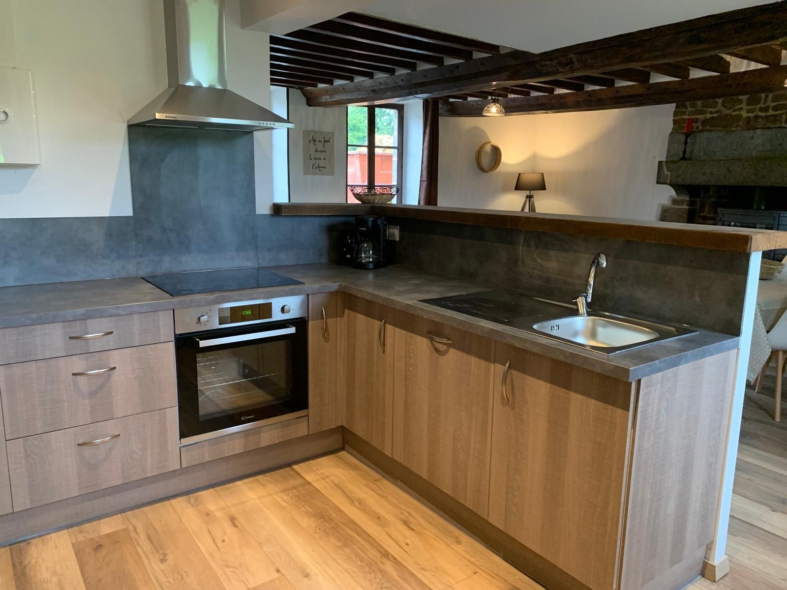 Een keuken met een inbouwoven, een spoelbak, houten kastjes en een stenen muur.