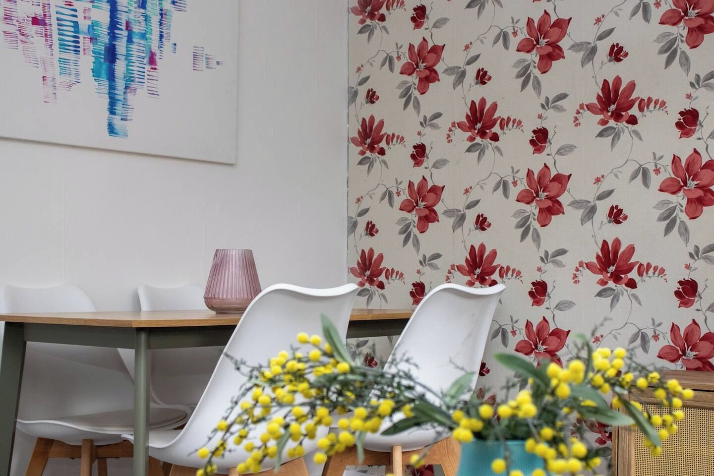 Een eetgedeelte met een tafel, stoelen en bloemenbehang.