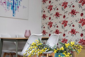 Uma sala de jantar com mesa, cadeiras e papel de parede floral.