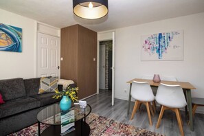 A modern living room with a sofa, a coffee table, and a dining area with chairs and a table. - East Kilbride 3BR Retreat | Free Parking |Sleeps 6 (East Kilbride)