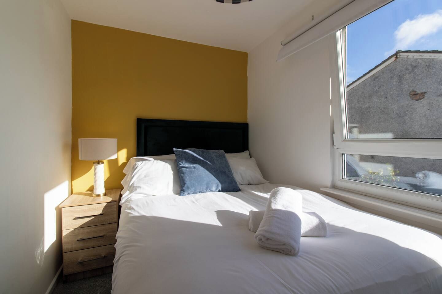 Une chambre d’hôtel avec un lit, une table de chevet, une lampe et une fenêtre.