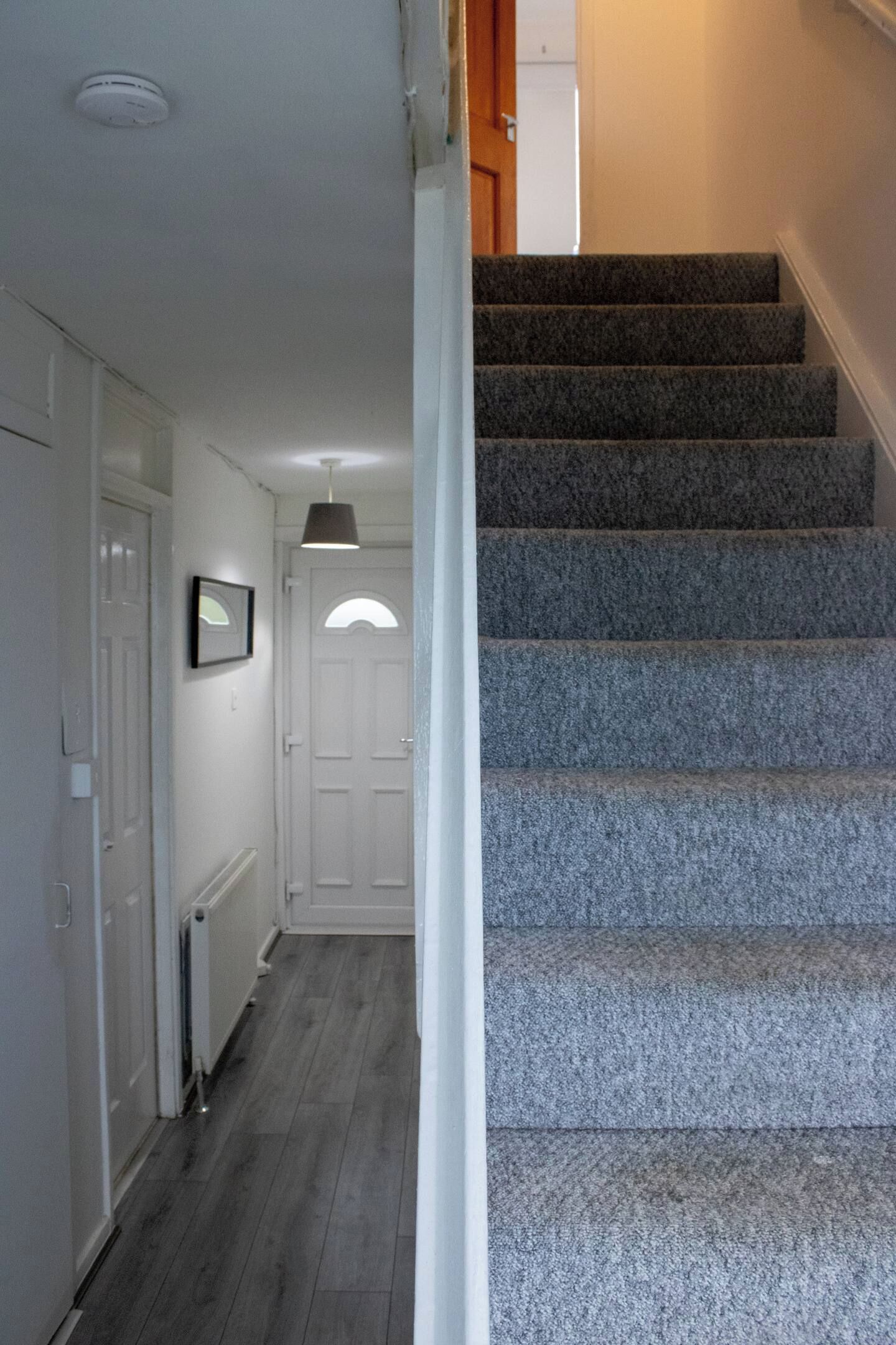 Un escalier dont les marches sont recouvertes de moquette, menant à un palier avec une porte.