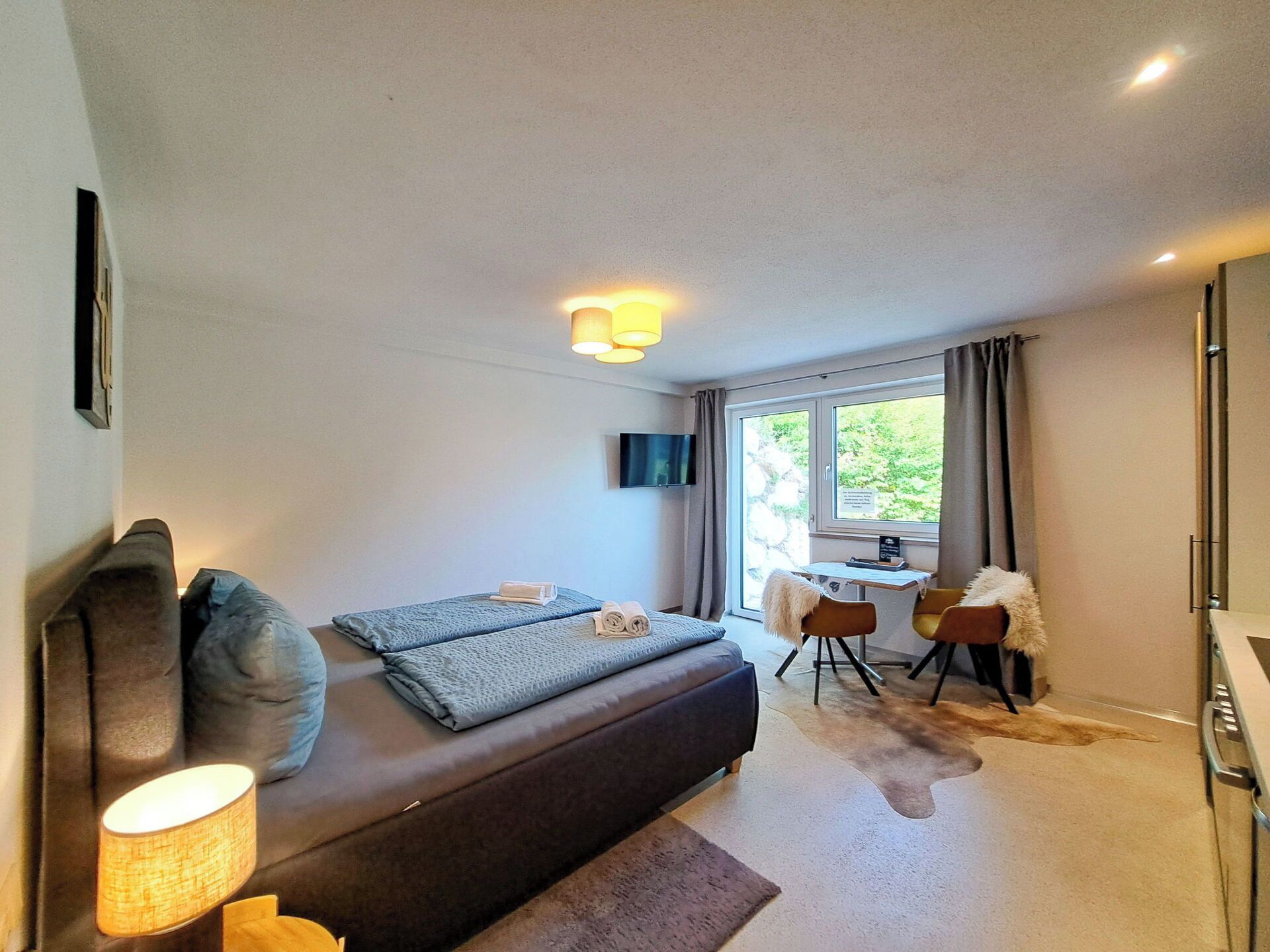 A modern hotel room with a bed, a desk, and a TV.